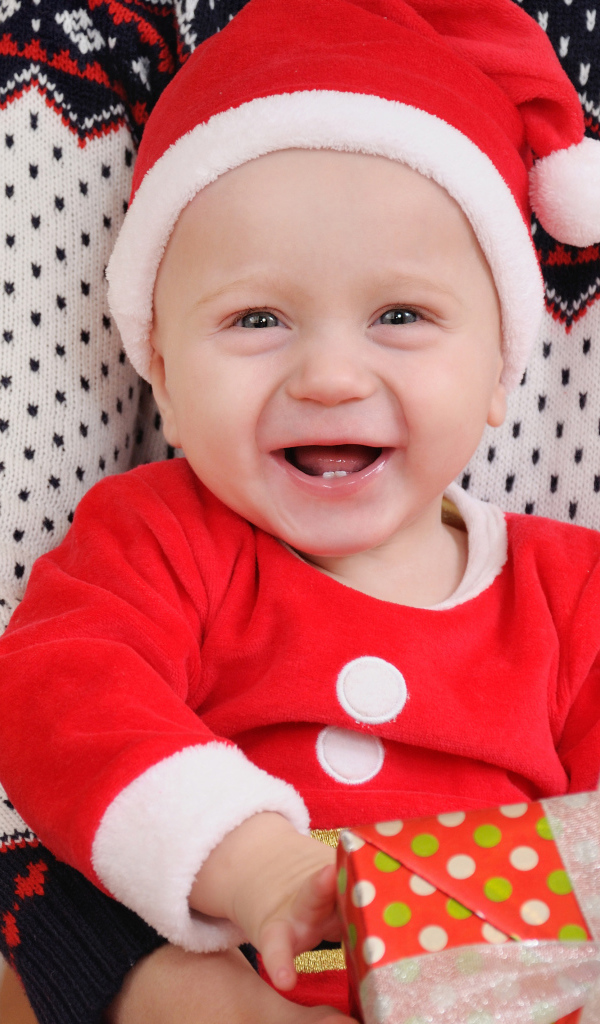 Улыбающийся малыш в костюме с подарком на руках 