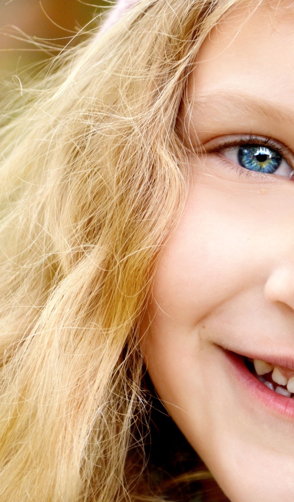 Улыбающаяся светловолосая девочка с голубыми глазами крупным планом