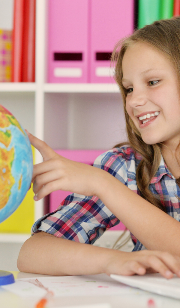 Улыбающаяся девочка школьница с глобусом