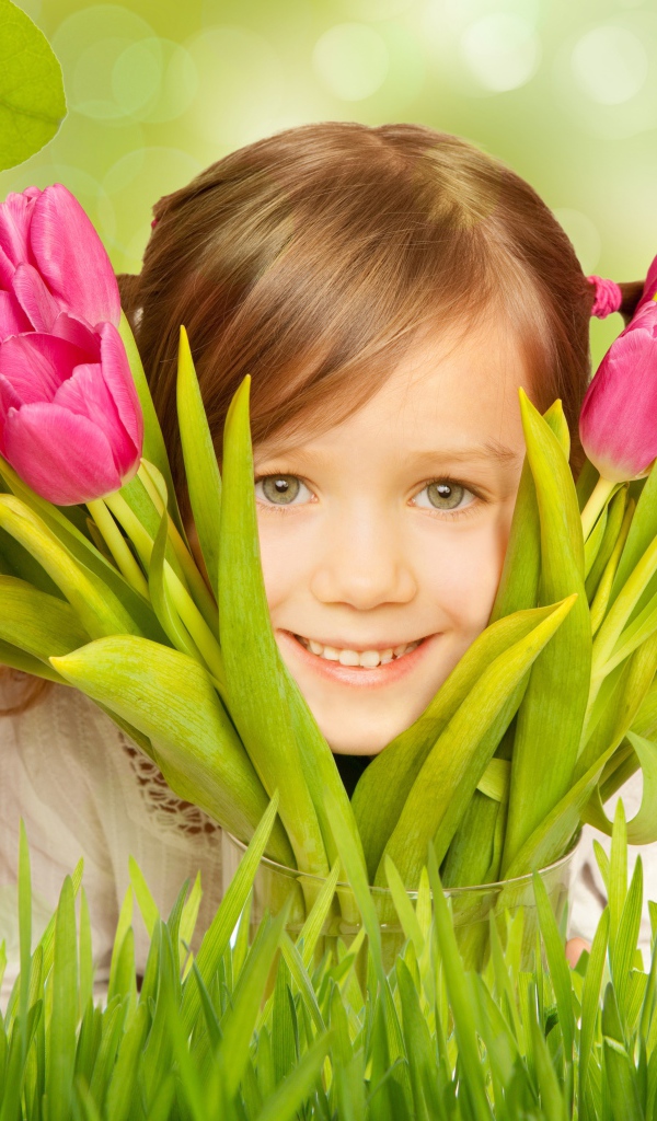 Улыбающаяся маленькая девочка с розовыми тюльпанами