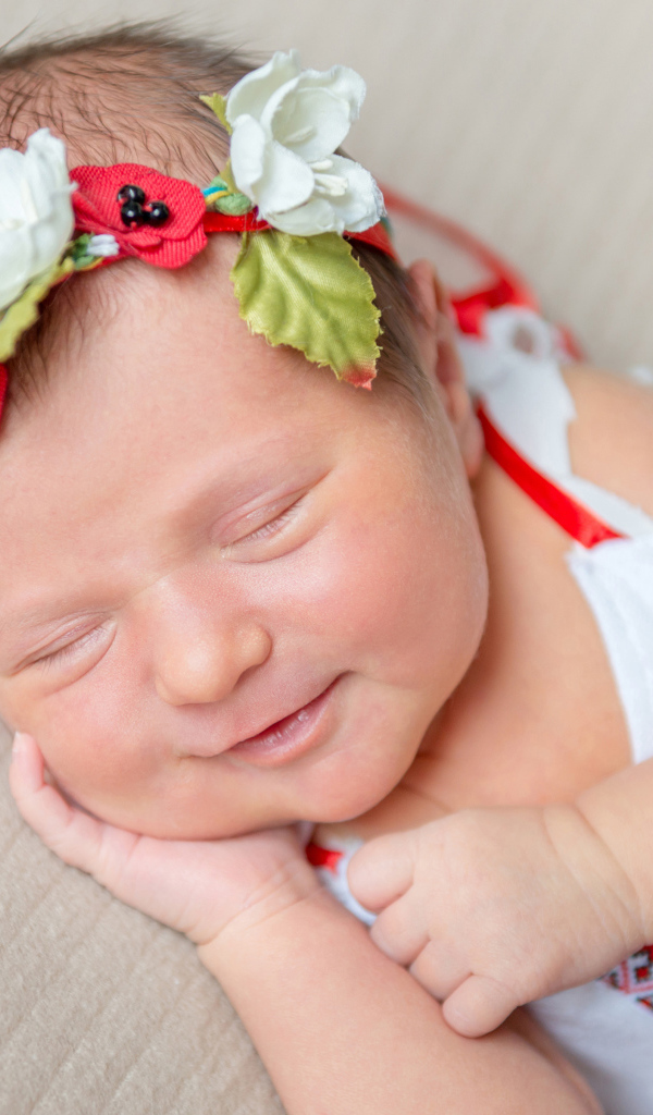 Улыбающаяся спящая девочка с венком на голове
