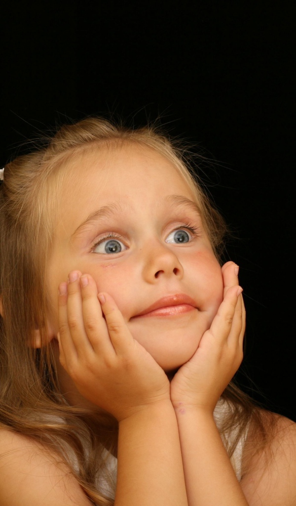 Удивленная маленькая девочка на черном фоне