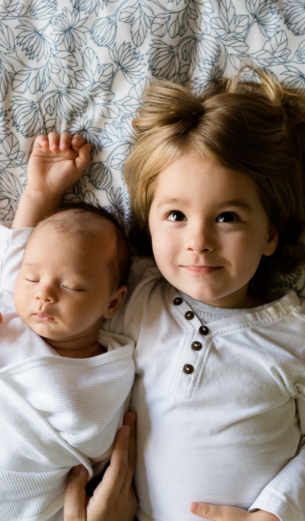 Маленькая девочка лежит с грудным ребенком