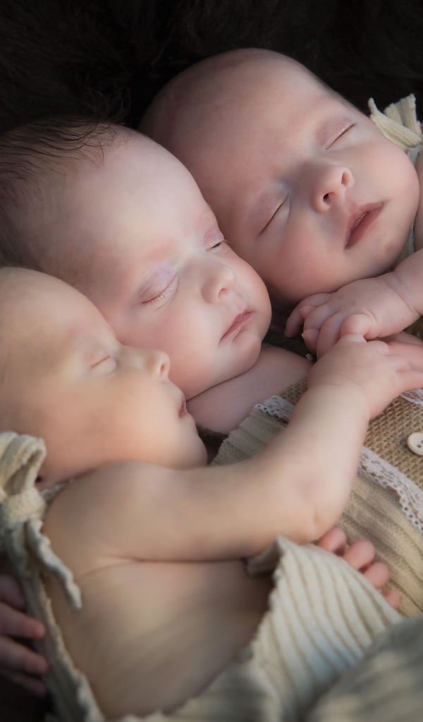 Три маленьких грудных ребенка спят обнявшись 
