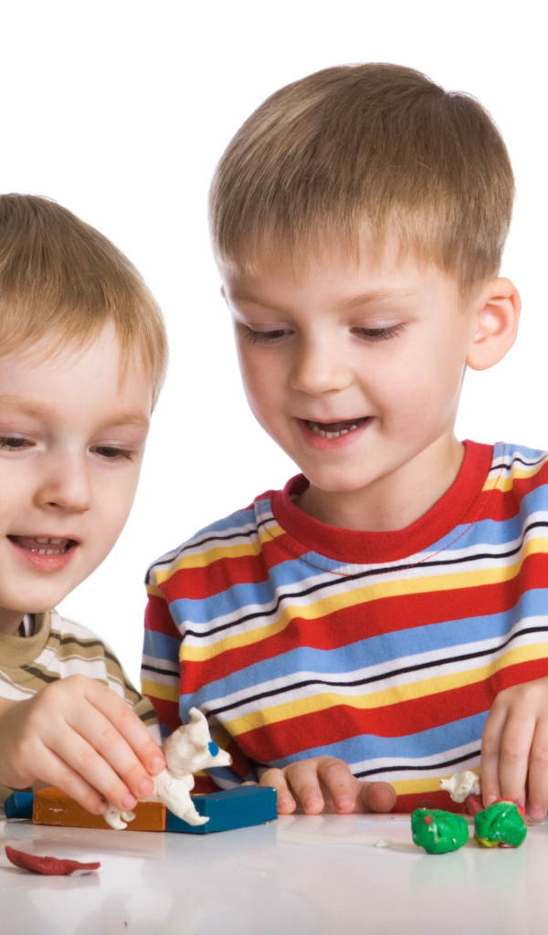 Два мальчика играют в игрушки на белом фоне