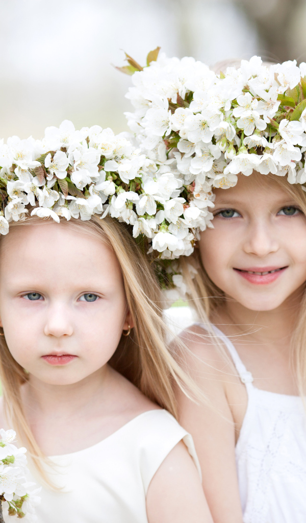 Две милые маленькие девочки с венками из цветов вишни на голове