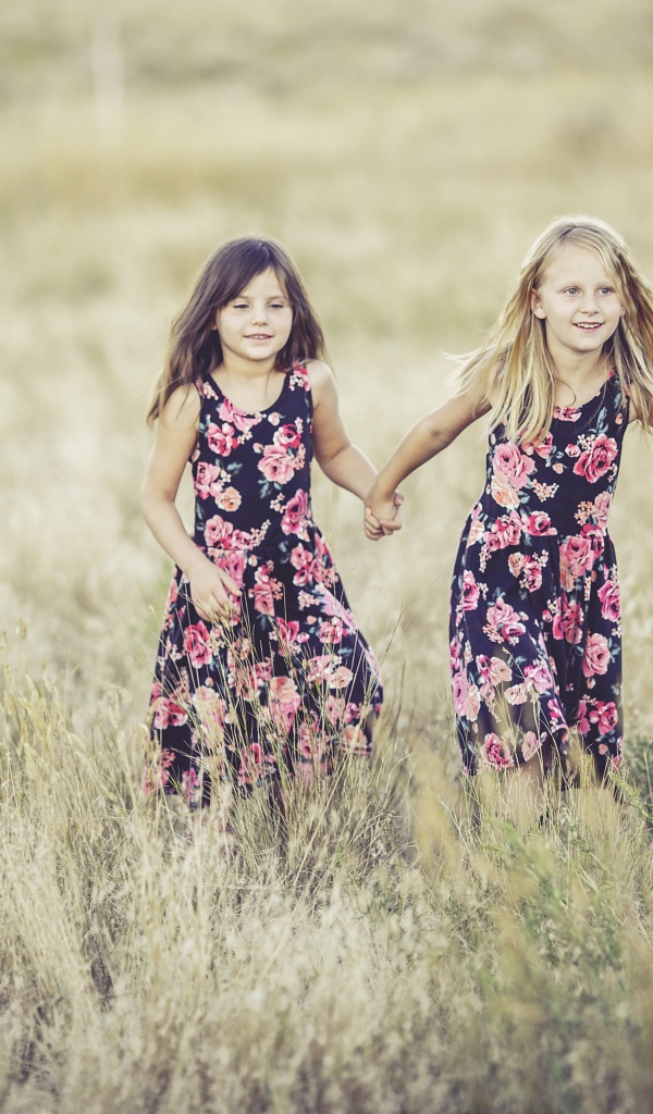 Две маленькие девочки бегут по траве