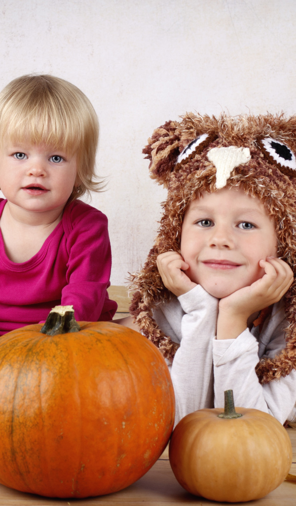 Два маленьких ребенка с тыквами в комнате