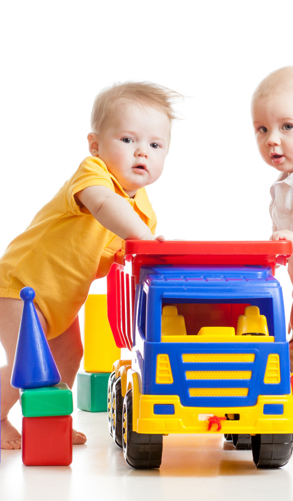 Два маленьких ребенка с игрушками на белом фоне