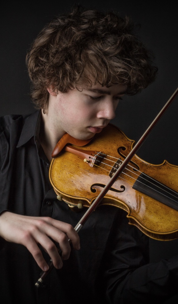 Молодой парень со скрипкой на черном фоне