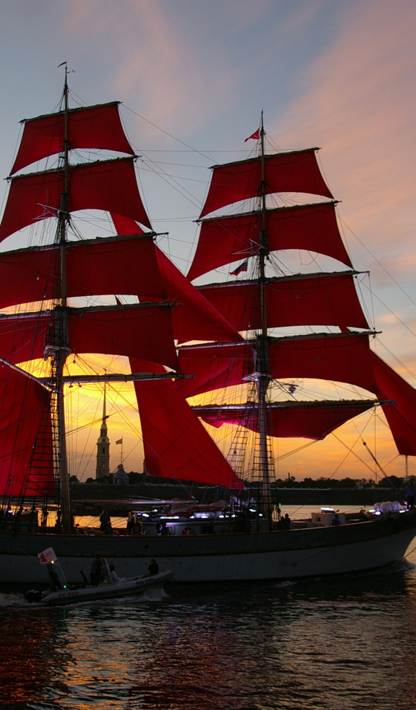 Big ship with red sails on sunset background