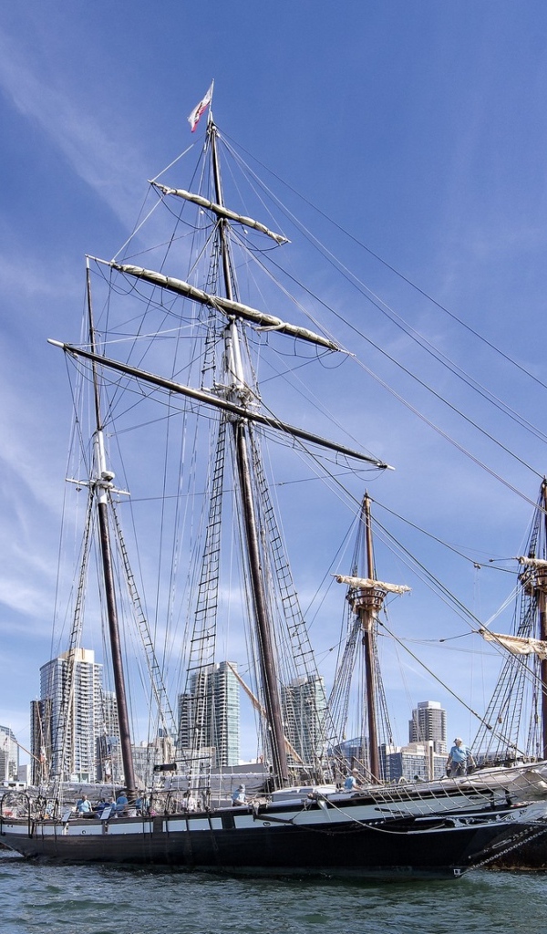 Большая парусная лодка на фоне голубого неба в порту у города