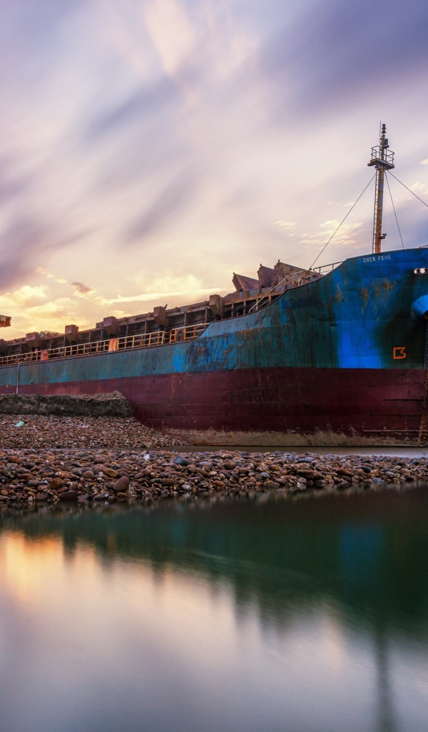 Old rusty ship on the shore under a beautiful sky