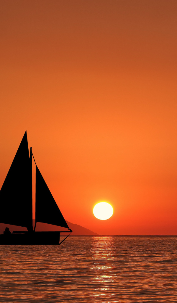 Парусная лодка в море на закате солнца