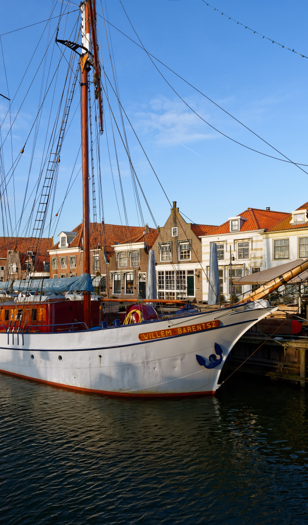 Парусное судно Willem Barentsz с опущенными парусами на причале у домов