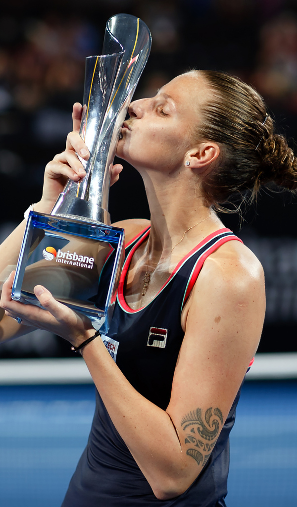 Чешская теннисистка Каролина Плишкова целует кубок на корте