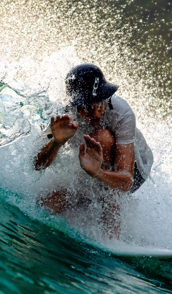 Парень серфингист ловит голубую морскую волну