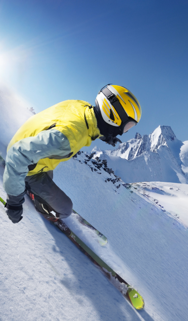 Лыжник в шлеме  спускается по заснеженному склону