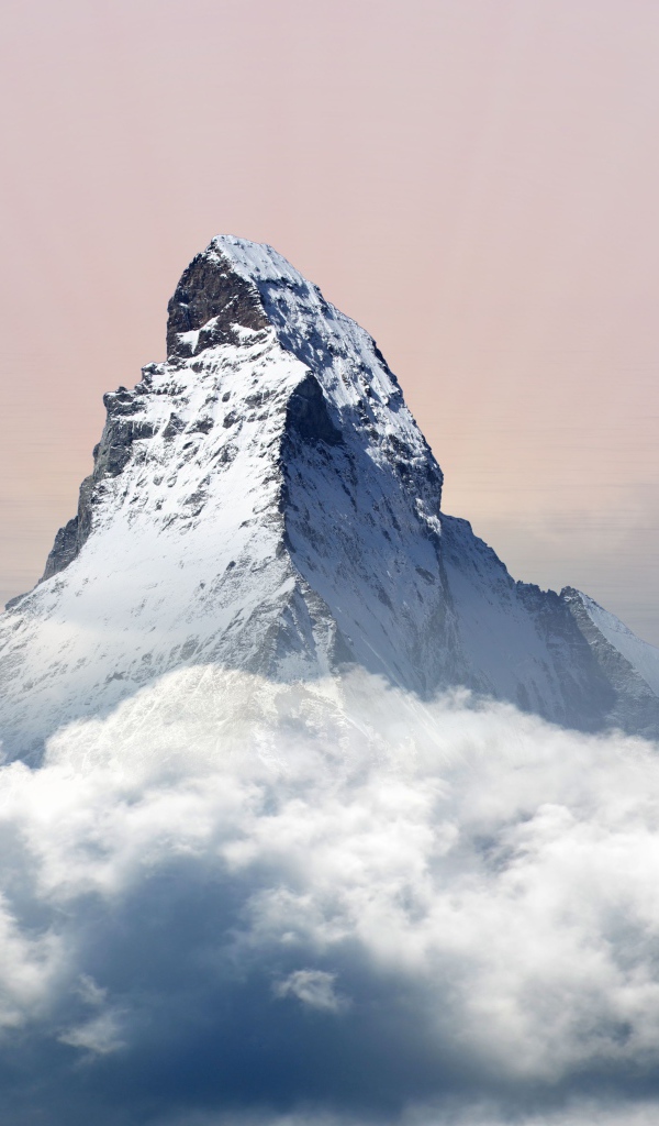 Заснеженная верхушка горы в белых облаках 