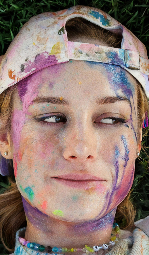 Актриса Бри Ларсон с лицом в краске лежит на траве