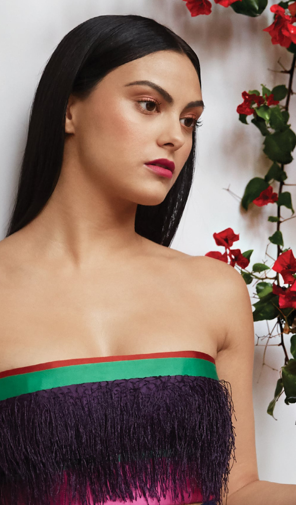 Актриса Камила Мендес стоит у стены с цветами