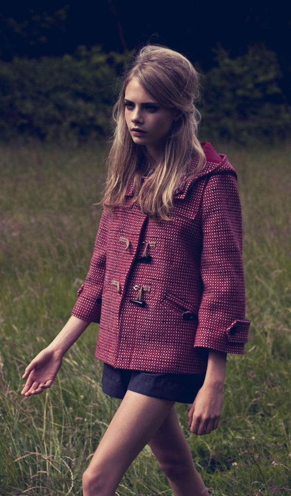 Актриса Кара Делевинь идет по траве в пальто 