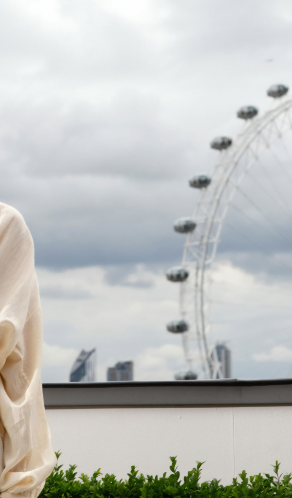 Актриса Марго Робби на  фоне аттракциона  колесо обозрения