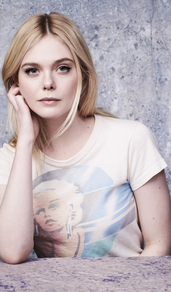 Красивая актриса Эль Фаннинг сидит за столом