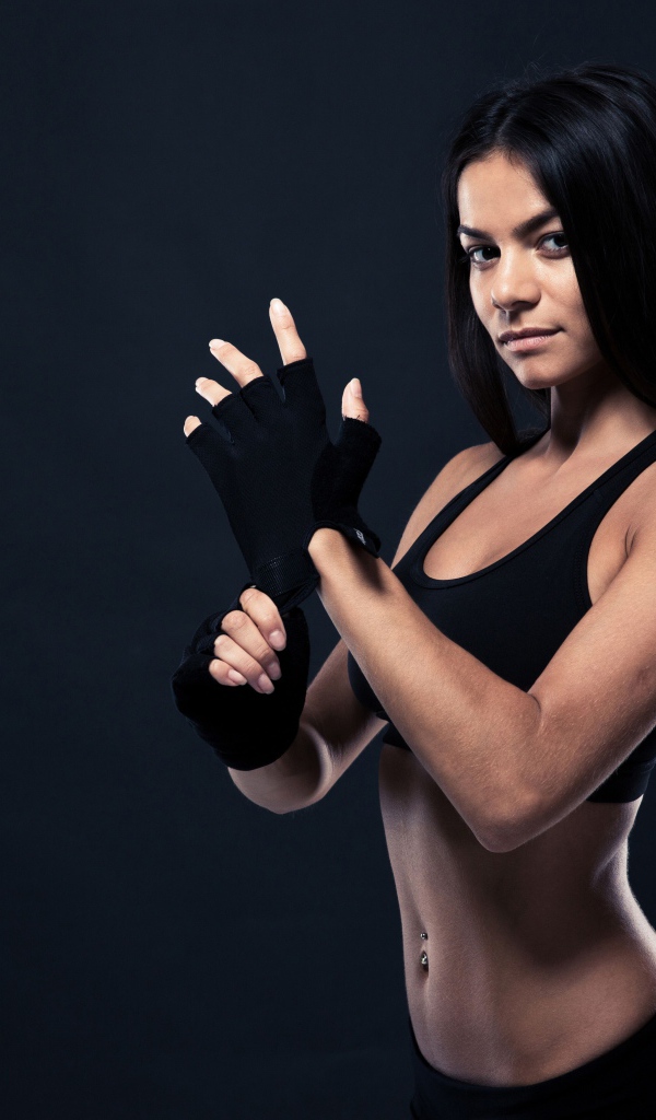 Красивая спортивная девушка в перчатках на сером фоне