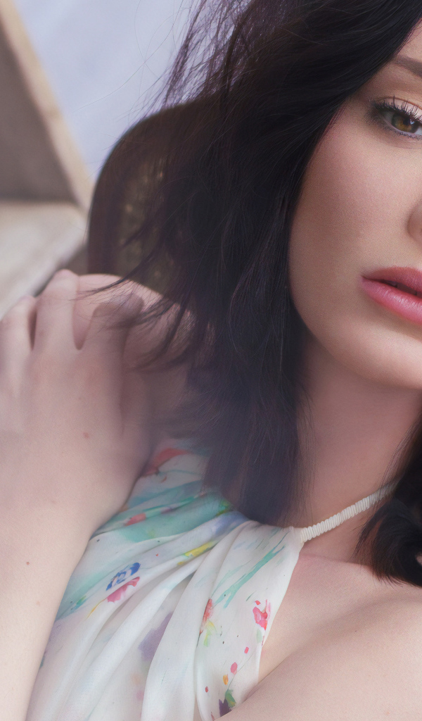 Красивая брюнетка, актриса Эмма Дюмон сидит на стуле 