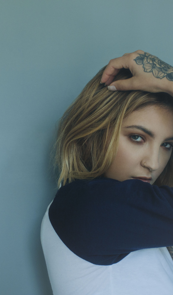 Красивая девушка стоит с татуировками на руке 