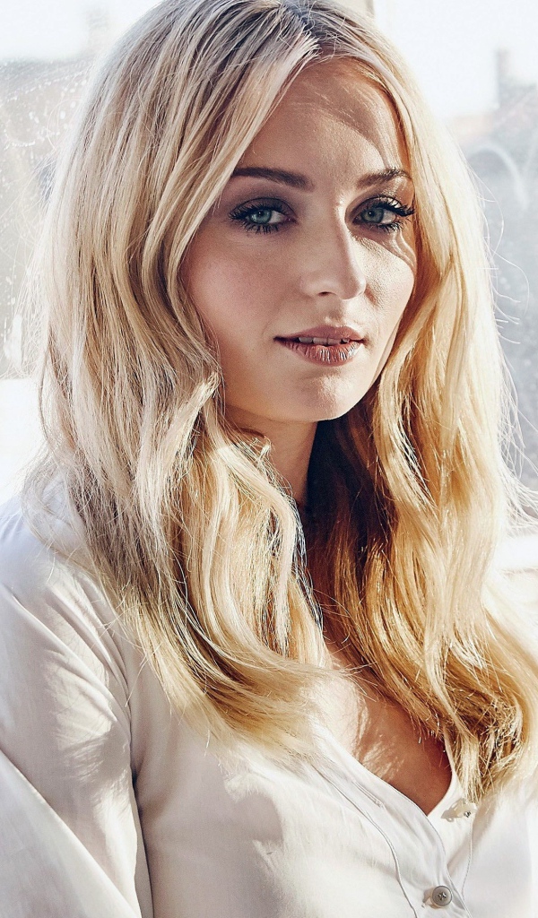 Красивая зеленоглазая блондинка, актриса Софи Тёрнер у окна