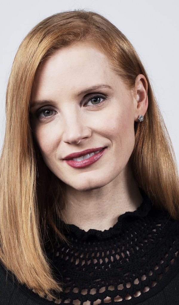 Красивая рыжеволосая актриса Джессика Честейн на сером фоне