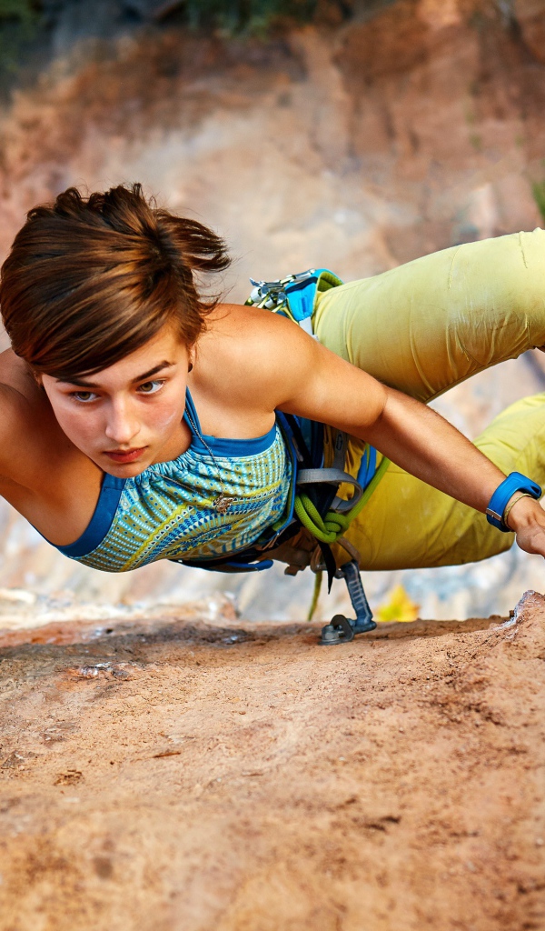 Девушка скалолаз лезет на гору 