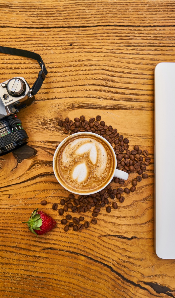 Чашка кофе на столе с фотоаппаратом и ноутбуком
