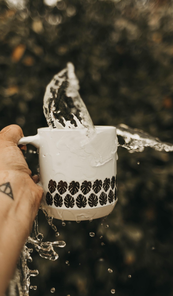 Чашка с водой в руке с татуировкой 