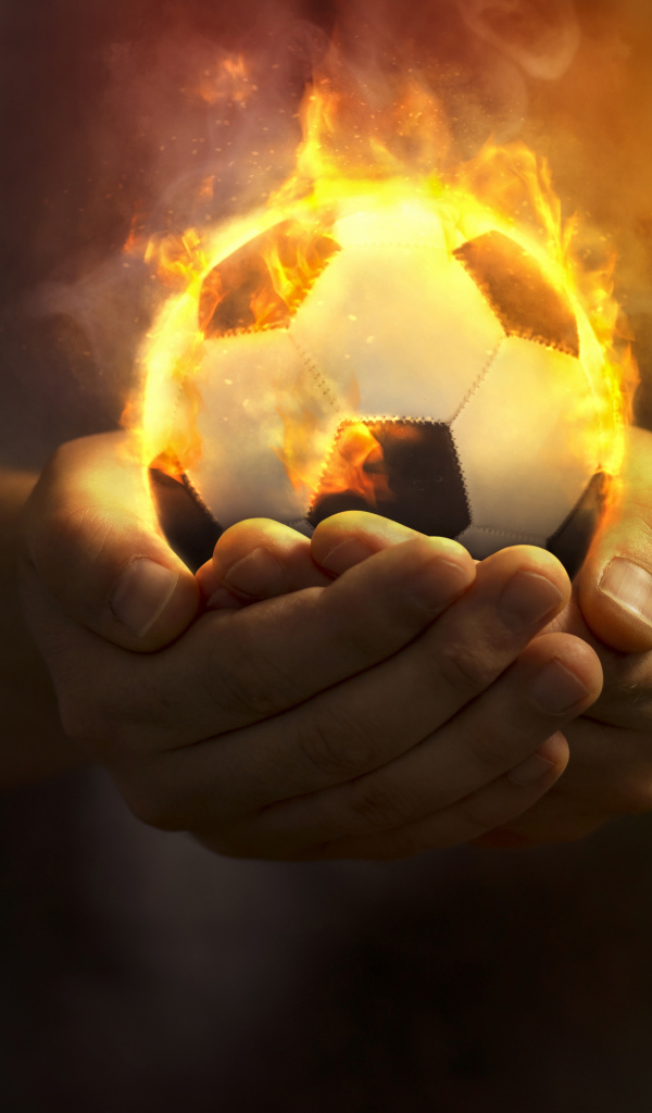 Огненный футбольный мяч в руках 