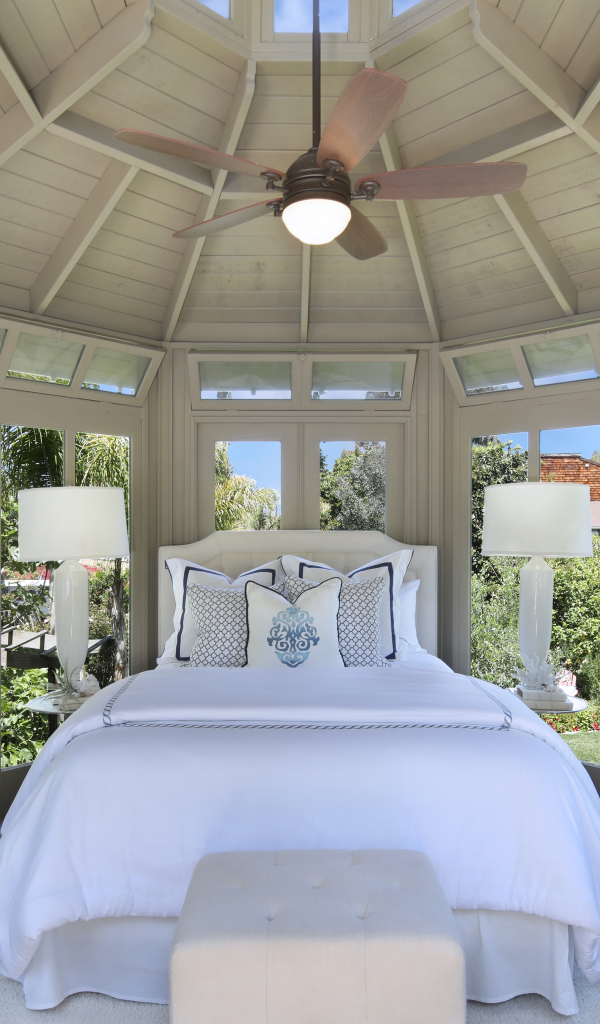 Большая спальная комната с окнами и белой кроватью 