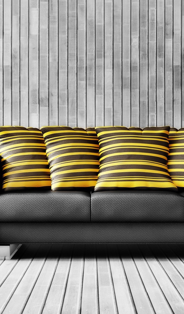 Большой черный кожаный диван с подушками у стены