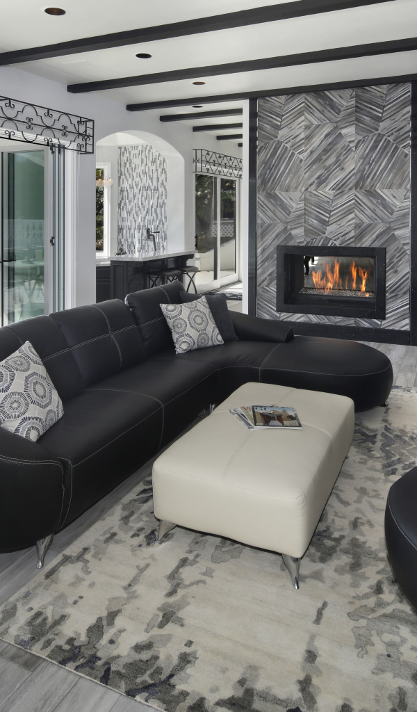 Большая просторная гостиная с черными кожаными диванами, телевизором и камином 