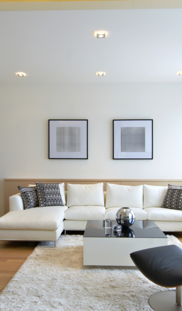 Гостиная комната с белым кожаным диваном и черным креслом у окна