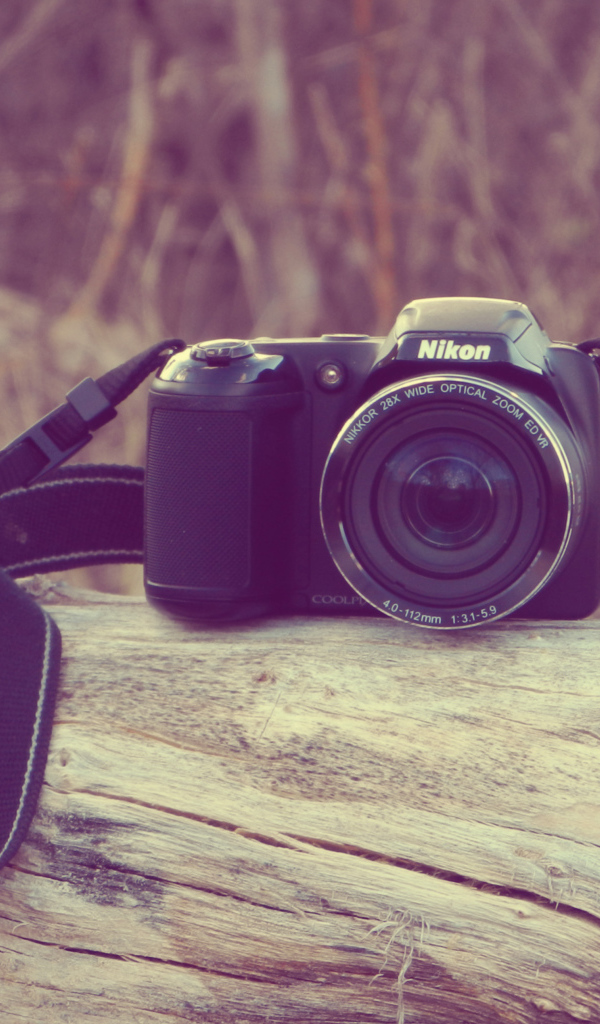Фотоаппарат Nikon лежит на сухом дереве