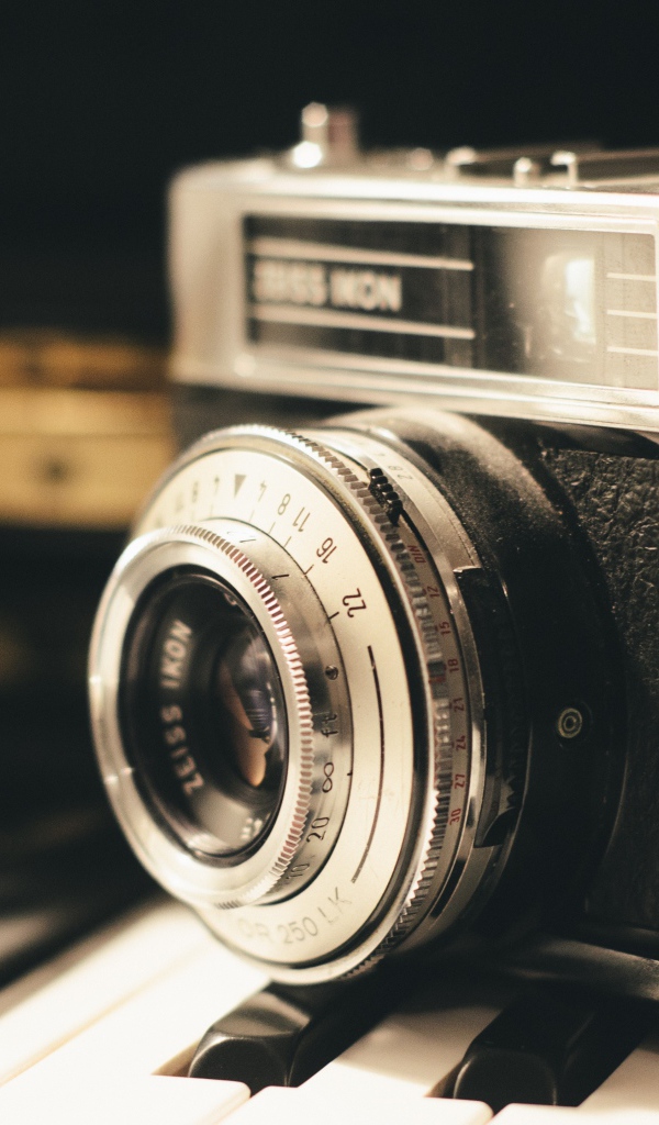 Старый фотоаппарат Zeiss Ikon стоит на клавишах пианино