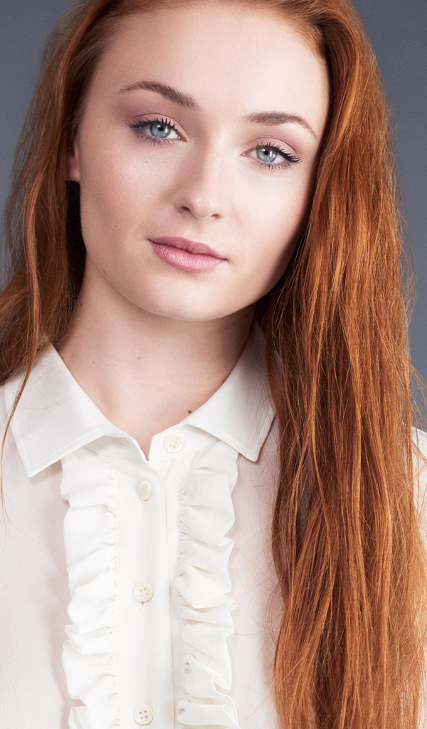 Рыжеволосая голубоглазая актриса Софи Тёрнер на сером фоне