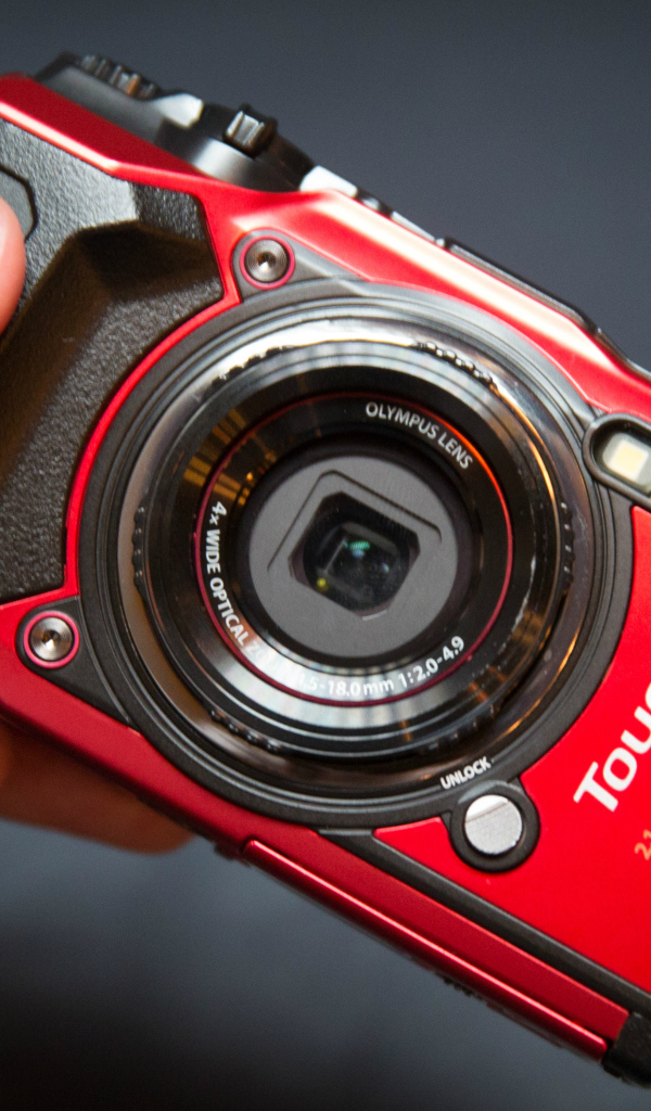 Red Olympus Tough TG-5 in hand on gray background