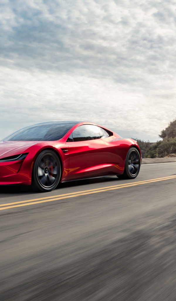 Красный автомобиль Tesla Roadster едет по трассе 