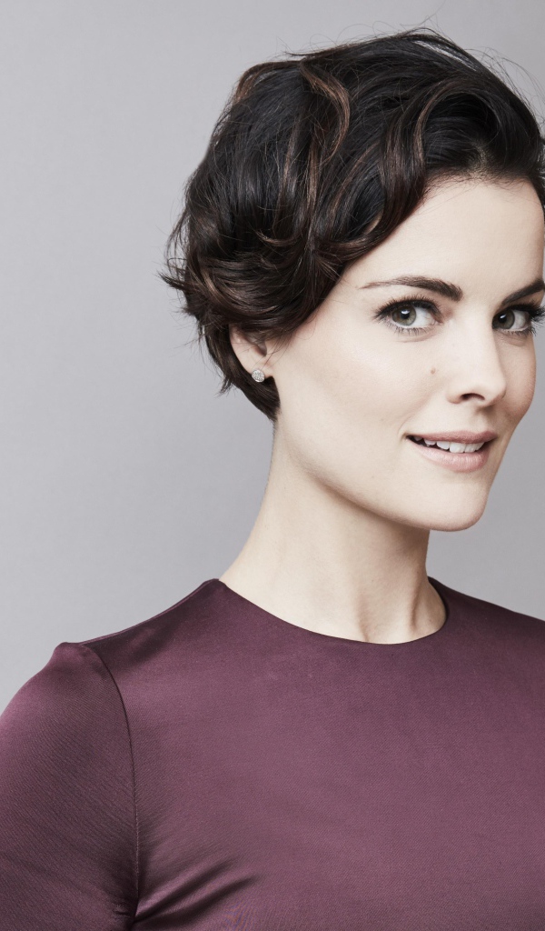 Улыбающаяся девушка, актриса Джейми Александр на сером фоне