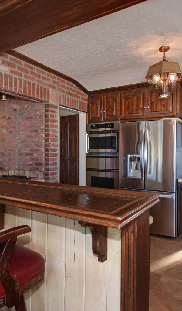 Просторная кухня с деревянной мебелью и кожаными стульями