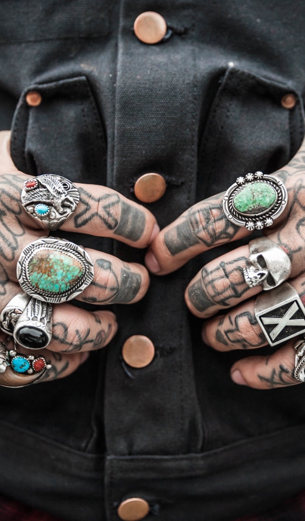 Татуировки на руках мужчины с перстнями