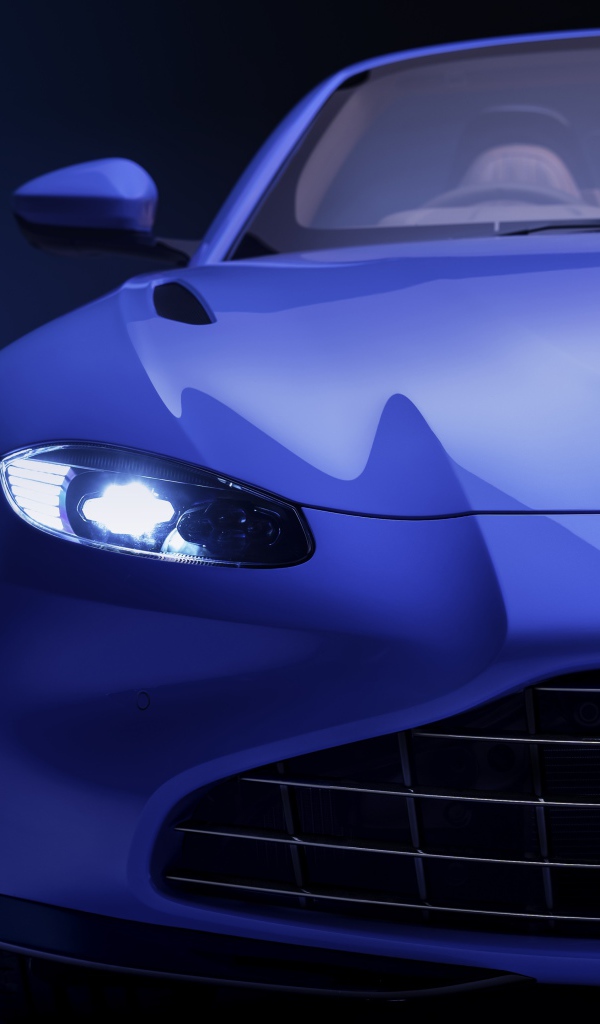 Синий автомобиль Aston Martin Vantage Roadster 2020 года с включенной фарой 